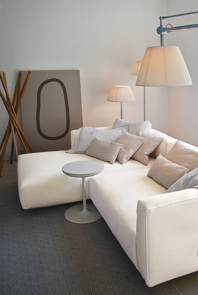 Toi side table with a round white top and central leg, in a living room.