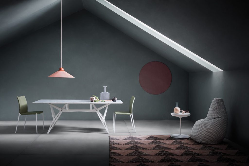Toi side table with a round white top and central leg, in a living room.