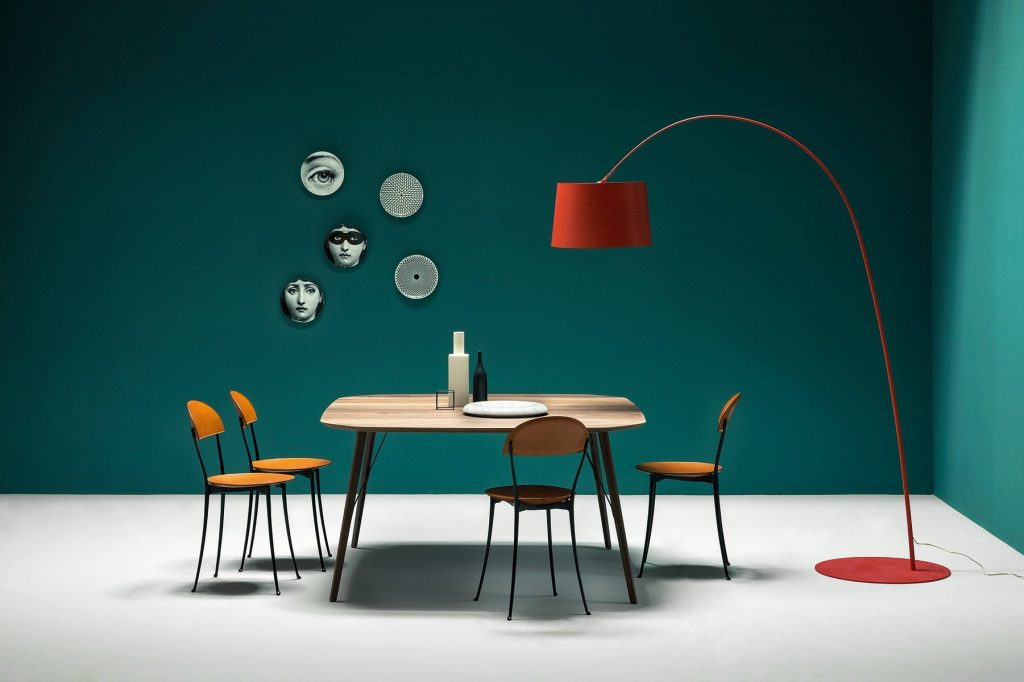 Four Tonietta chairs featuring a orange cushioned seat and backrest, and black metal frame in a dining room.
