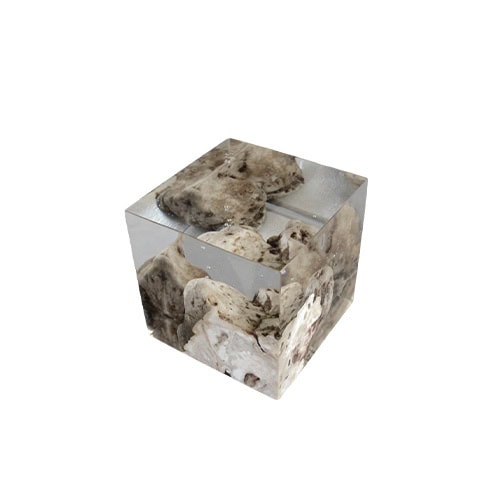 A cube-shaped bookend of resin and natural karst stone creates a striking effect with rocks appearing suspended inside. The piece combines weight, stability, and sculptural presence, serving both function and decoration.