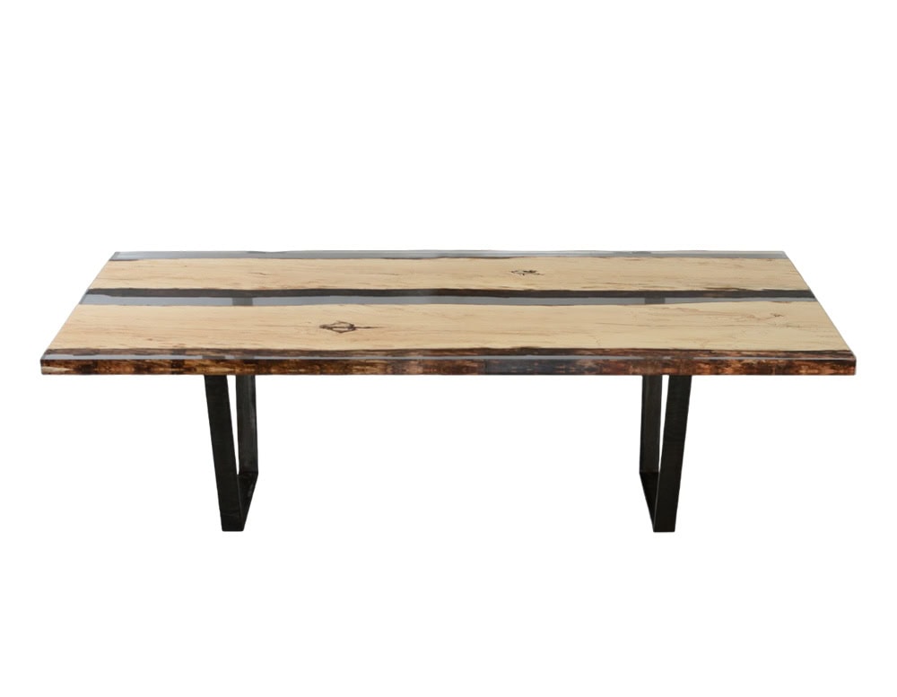 This dining table combines spalted wood and clear resin, highlighting organic patterns with a sleek modern finish. Supported by geometric black legs, it balances natural warmth with industrial edge.