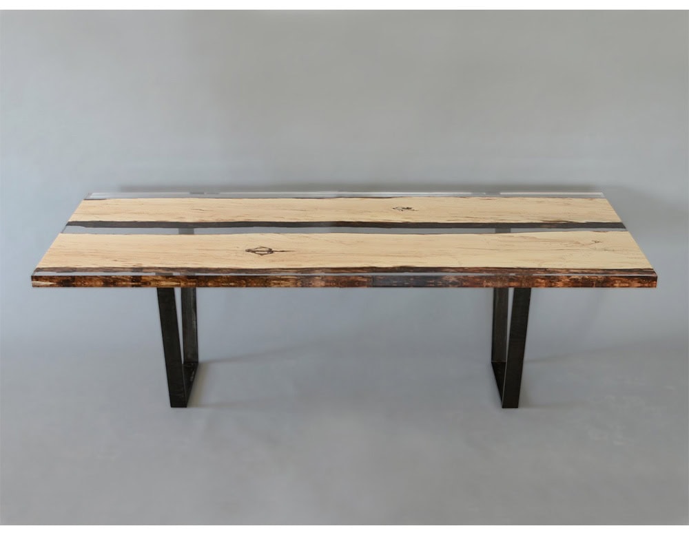 This dining table highlights spalted wood framed in clear resin, showcasing natural textures with a sleek modern edge. Its minimalist metal legs add stability, blending rustic charm with a refined contemporary look.