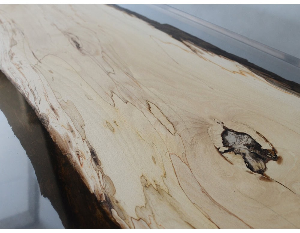 Crafted with spalted wood and clear resin, this piece highlights organic textures in a modern linear design. Supported by minimalist legs, it creates a striking balance of raw and refined elements.
