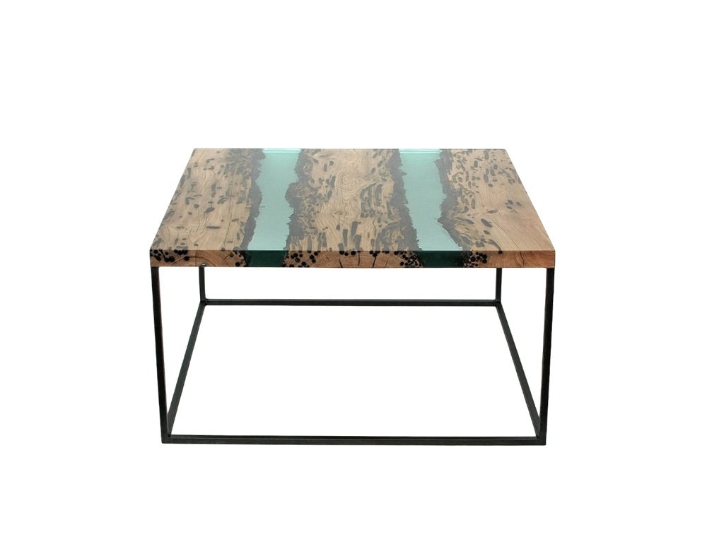 The Jetty Coffee Table combines raw wood marked with natural patterns and a translucent resin that evokes the effect of flowing water, all supported by a sleek black metal frame.