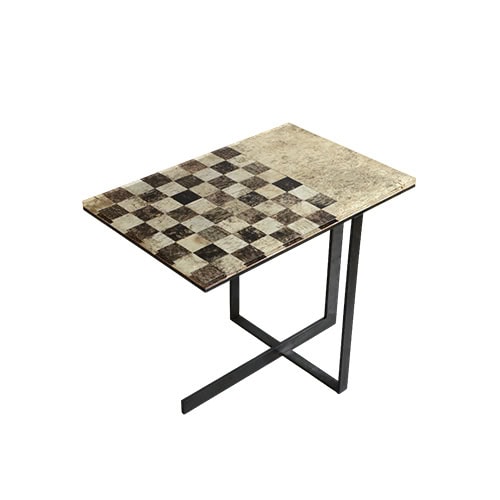 Phellem Chess Table pairs a cork chessboard top with intersecting metal legs. The natural grid of light and dark tones contrasts with its clean structure, creating a modern and functional accent.