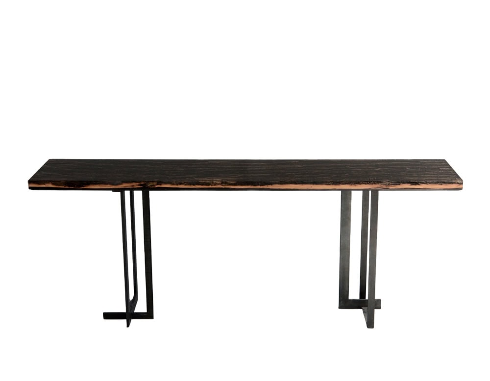 Phellem Console Table showcases a long dark wood top with raw edges, elevated by geometric metal legs. Its sleek form and natural surface bring together elegance and earthy character.