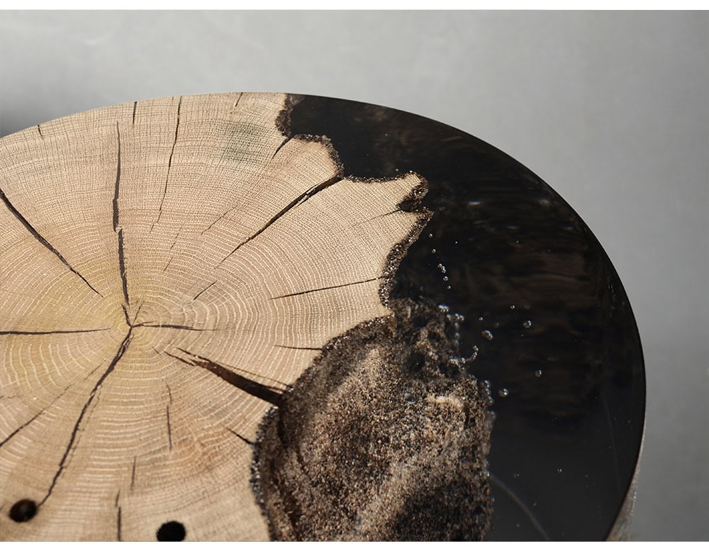 Surfacing Fisheye Stool captures the cross section of a tree trunk with rings and cracks sealed in resin. The organic surface contrasts with the glossy finish, giving it a sculptural presence.