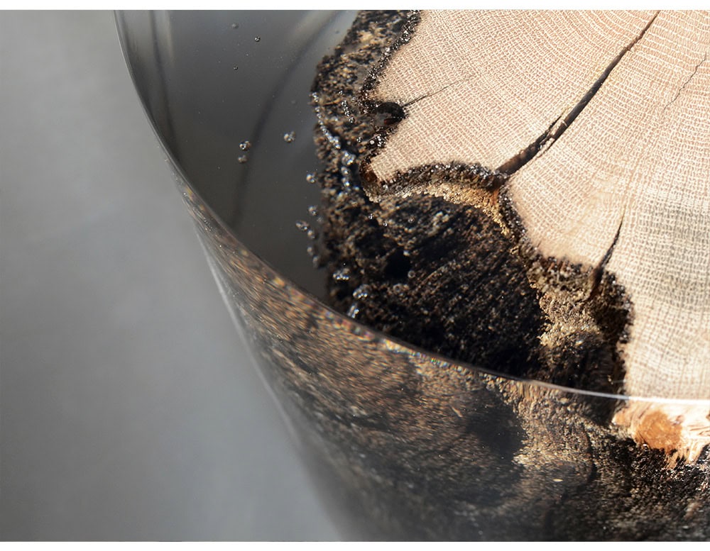 Surfacing Fisheye Stool highlights the natural grain and bark of a tree cross section, preserved in resin. The glossy surface enhances organic textures, turning it into a functional sculpture.