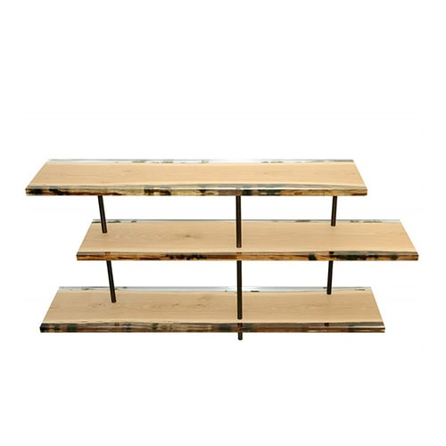 The Woodpile Shelving features three solid wood planks supported by vertical steel rods, combining raw texture with minimalist structure. Its natural finish and clean geometry highlight a balance of function and sculptural presence.