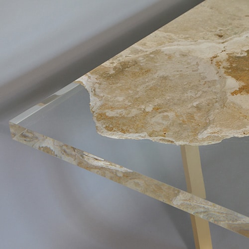 table made of travertine rock and glass in transparent and golden color tone