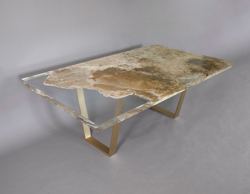 table made of travertine rock and glass in transparent and golden color tone on a gray background