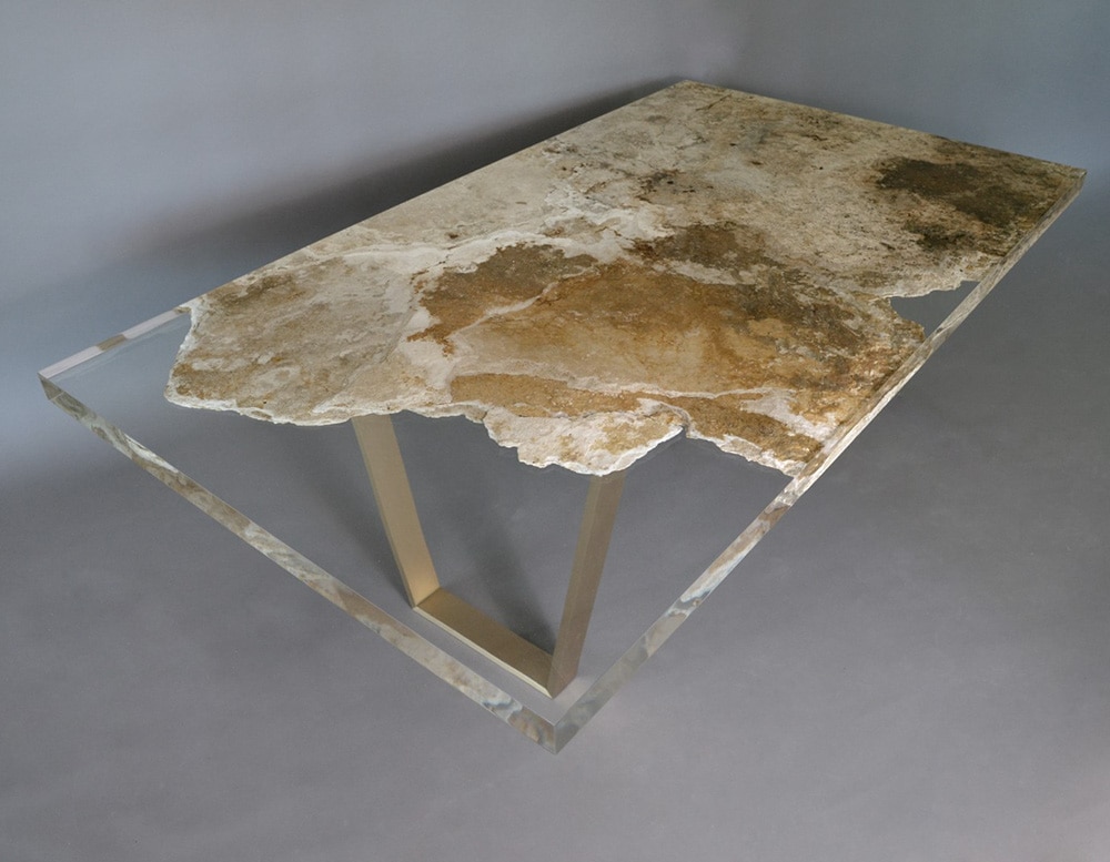 table made of travertine rock and glass in transparent and golden color tone