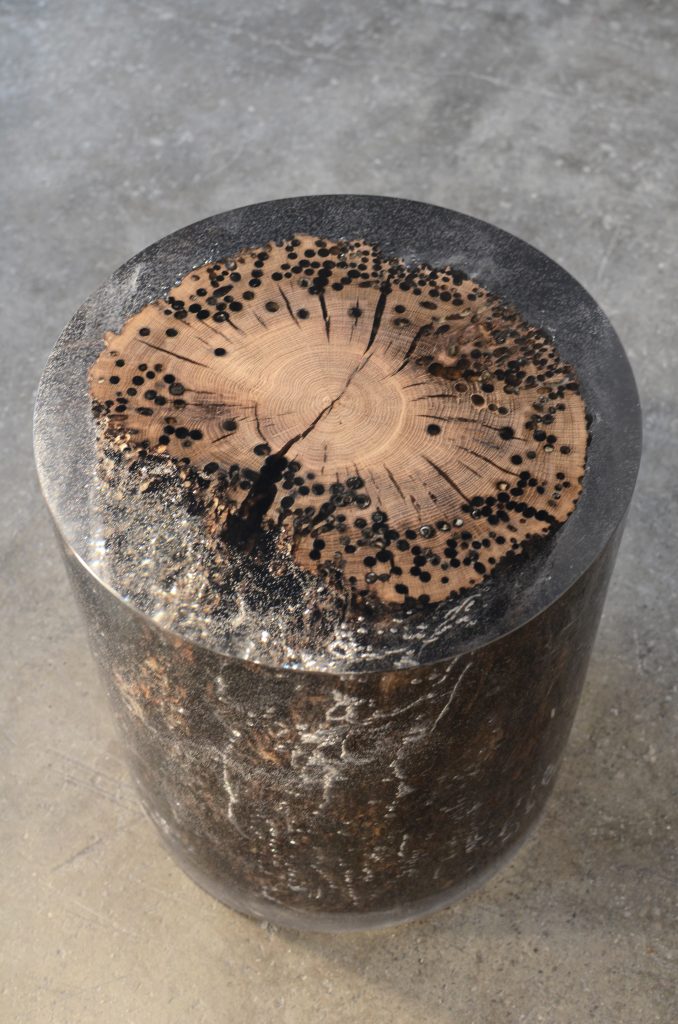 Fisheye Stool/Side Table with a rounded shape, made of solid wood with a natural finish, set against a gray background.