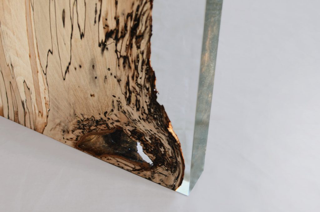 Closeup of Fungi Console with an elongated, rectangular shape, made of wood with a natural finish and featuring a transparent resin inlay, set against a white background.