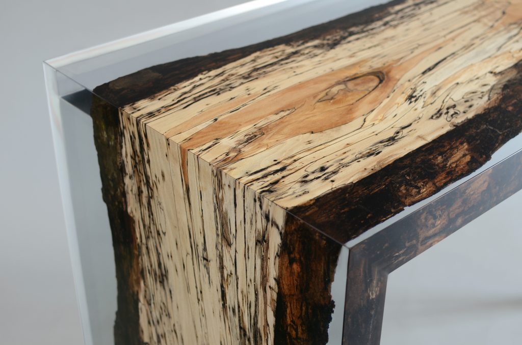 Closeup of Fungi Console with an elongated, rectangular shape, made of wood with a natural finish and featuring a transparent resin inlay, set against a white background.