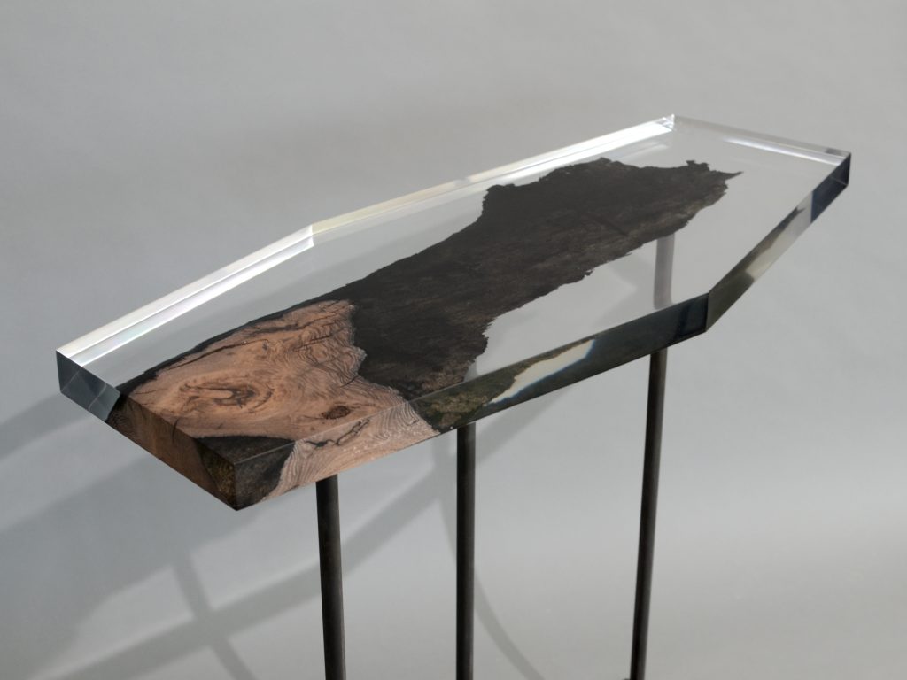 table made of resin and natural wood in the shape of a hexagon resting on a base of steel legs on a gray background