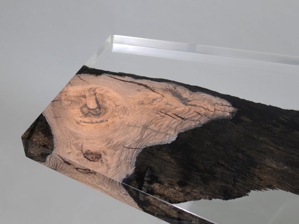 Natural wood table completely covered in transparent resin in the shape of a hexagon