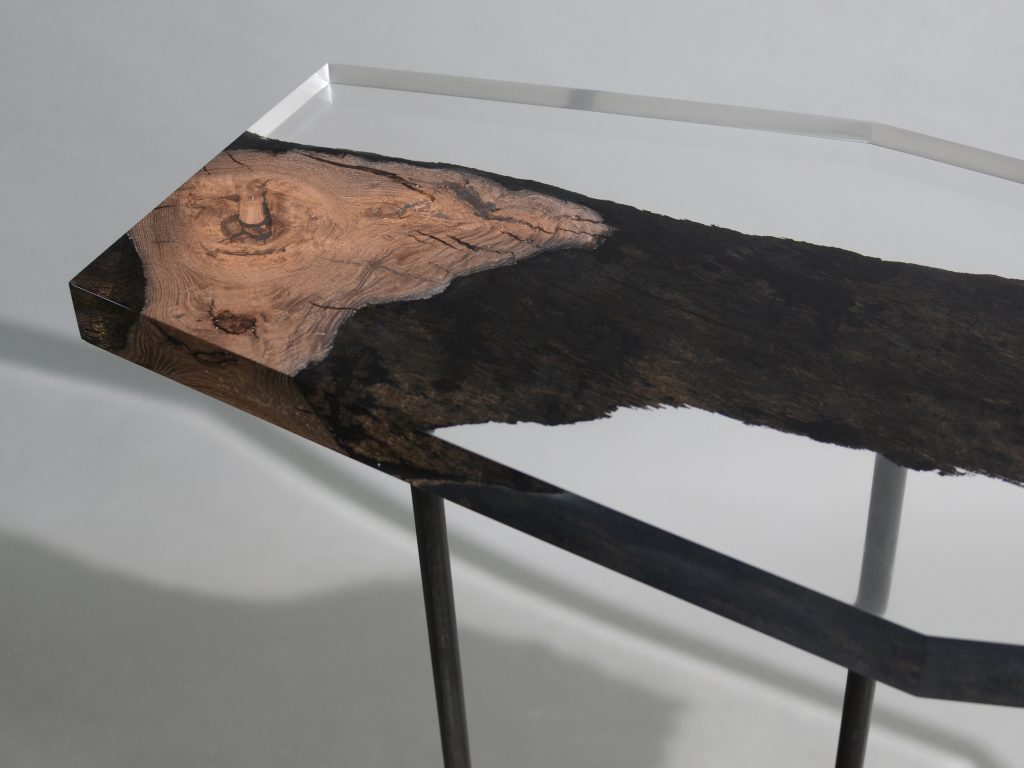Natural wood table completely covered in transparent resin in the shape of a hexagon on a grayu background