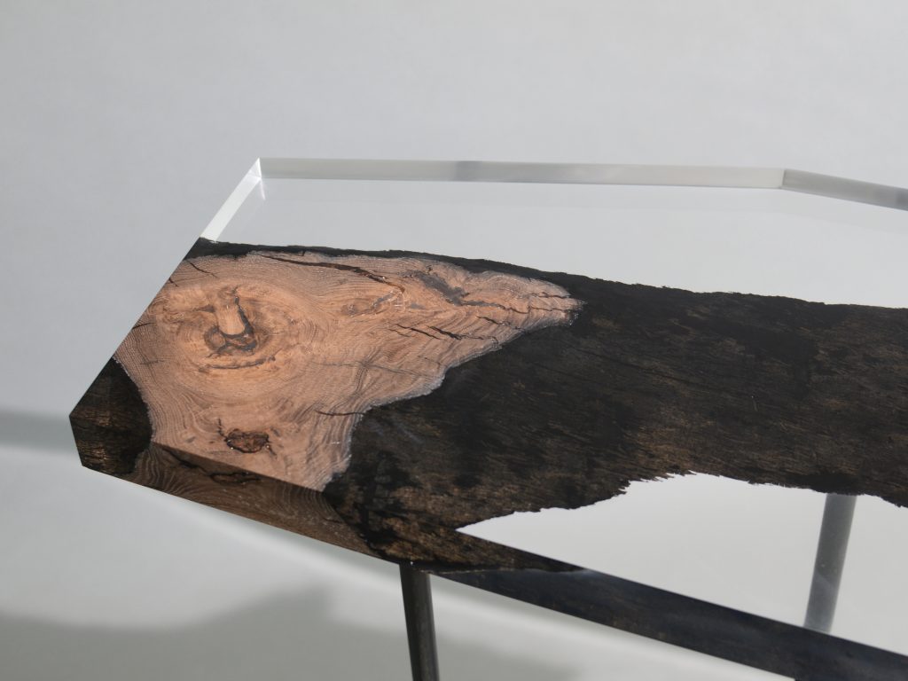 Natural wood table completely covered in transparent resin in the shape of a hexagon on a gray background
