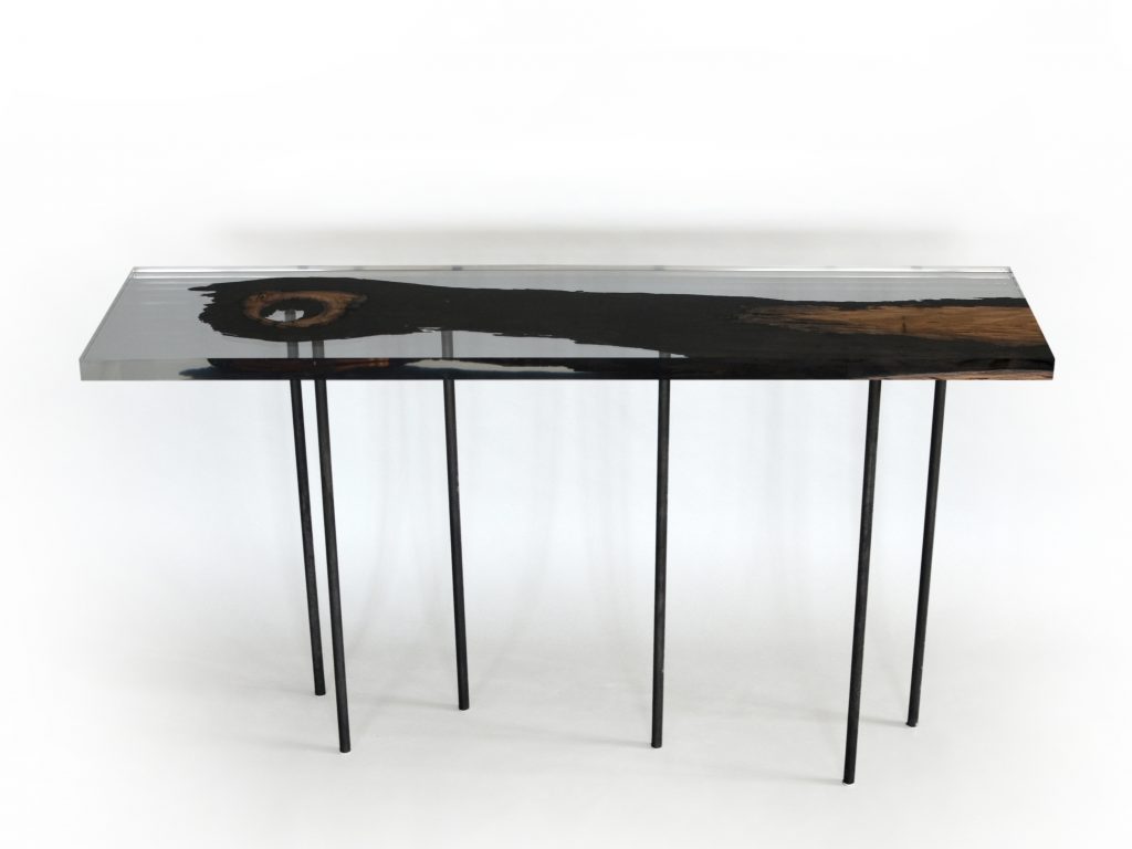 table made with a base of steel legs and a wooden top covered in resin in a brown and transparent tone on a white background