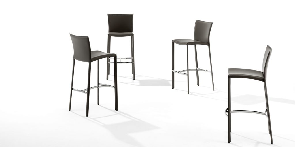 four bar stools made with steel legs and upholstered in dark gray leather on a white background