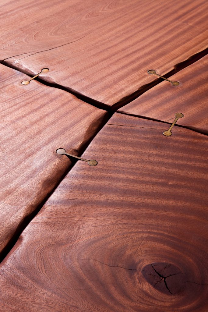 Closeup of Rectangle 10th Joint Dining Table in brown wood and materic slabs connected by burnished brass joint.