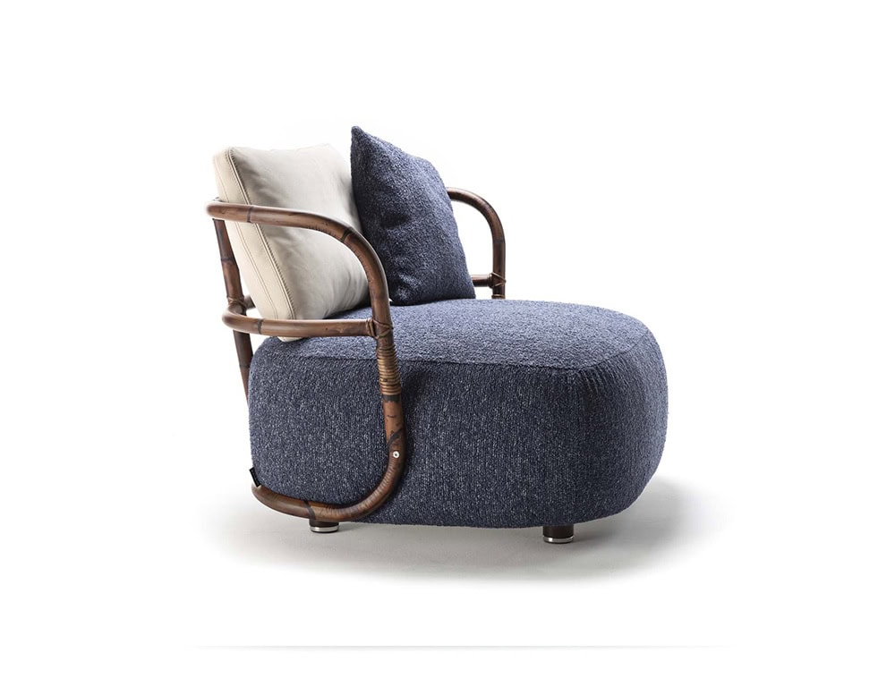 A side view of the Jungle Armchair showcasing its curved wooden frame woven backrest and plush blue cushion for a modern elegant design