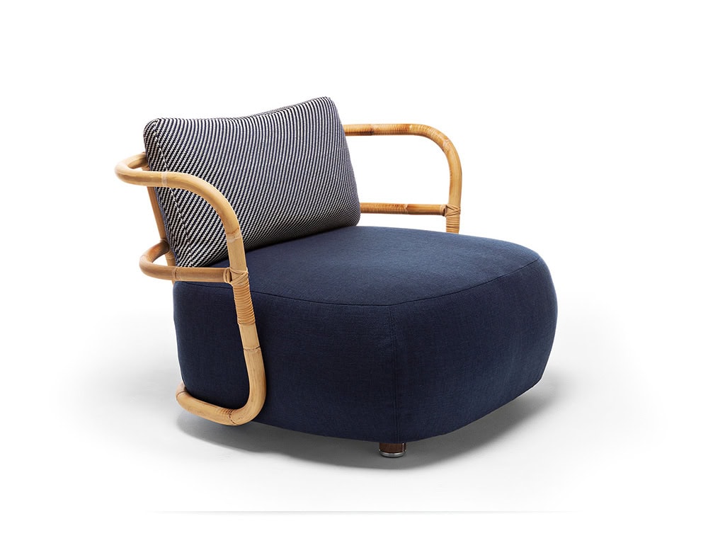 A studio shot of the Jungle Armchair featuring a curved wooden frame a woven backrest and a plush deep blue cushion for a stylish modern look