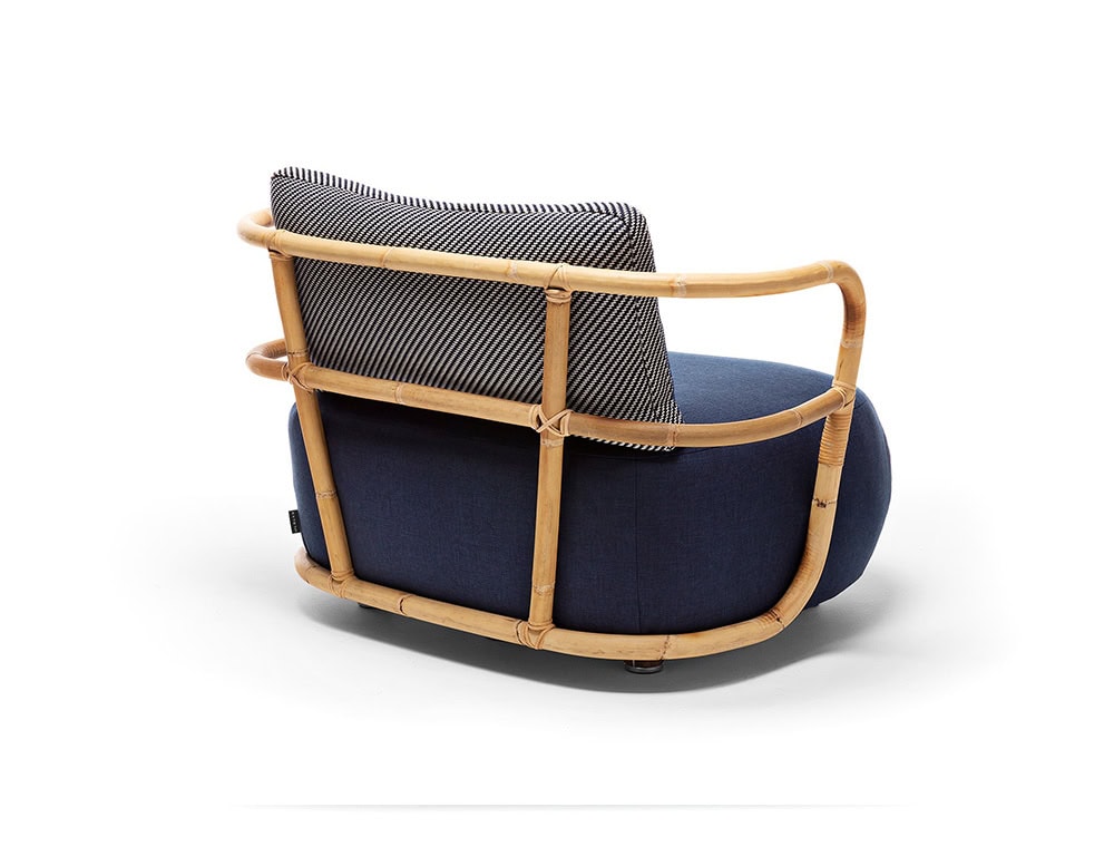 A rear view of the Jungle Armchair showcasing its elegantly curved wooden frame woven backrest and plush deep blue cushion
