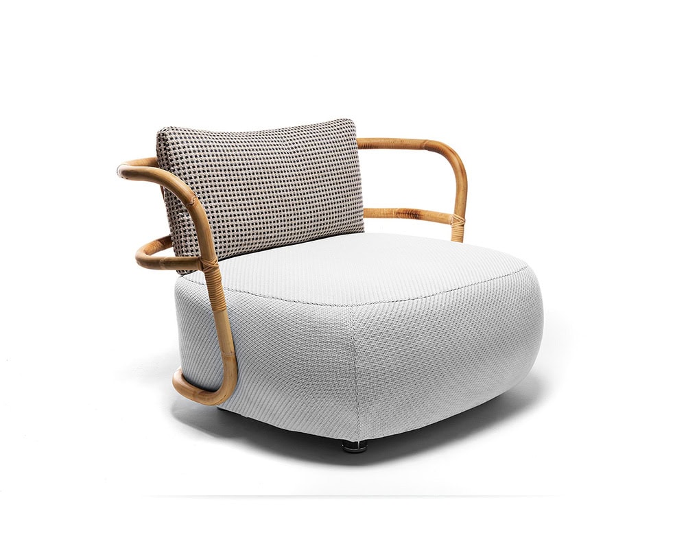 A studio shot of the Jungle Armchair featuring a curved wooden frame a woven backrest and a plush white cushion for a modern elegant look