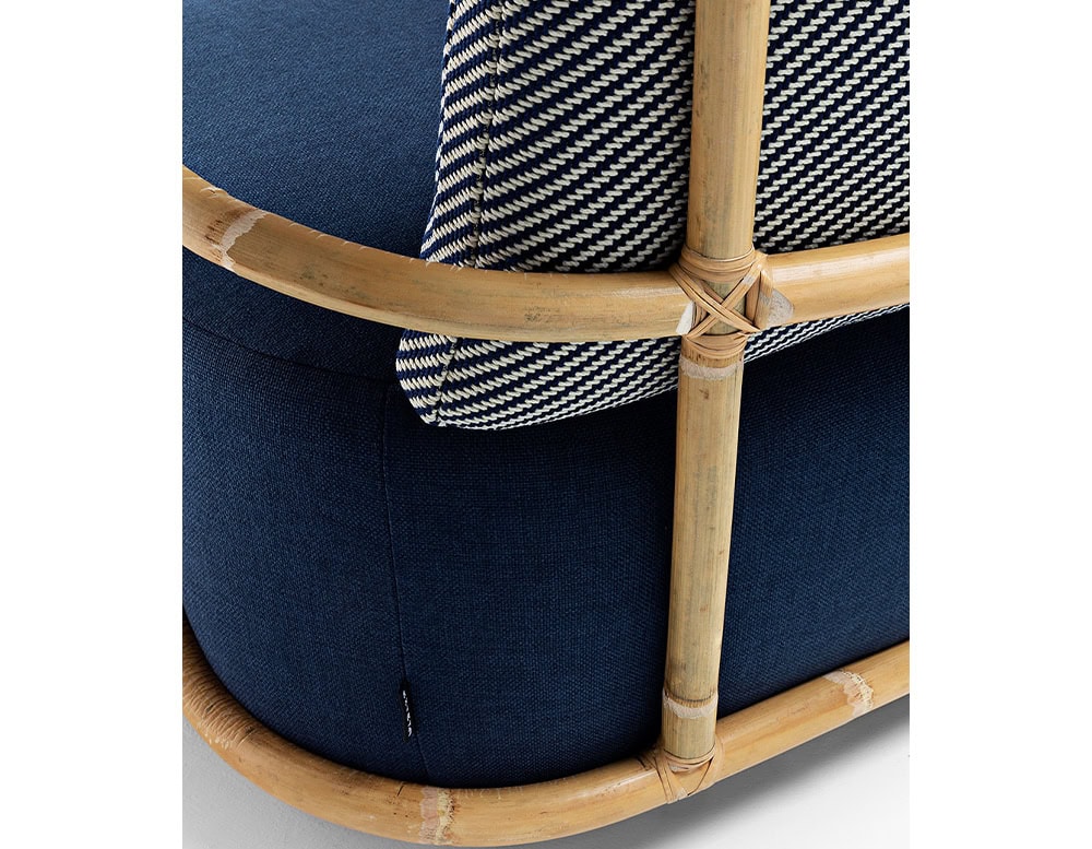Closeup of Jungle Armchair Slim upholstered in gray fabric and brown wooden structure on a white background.