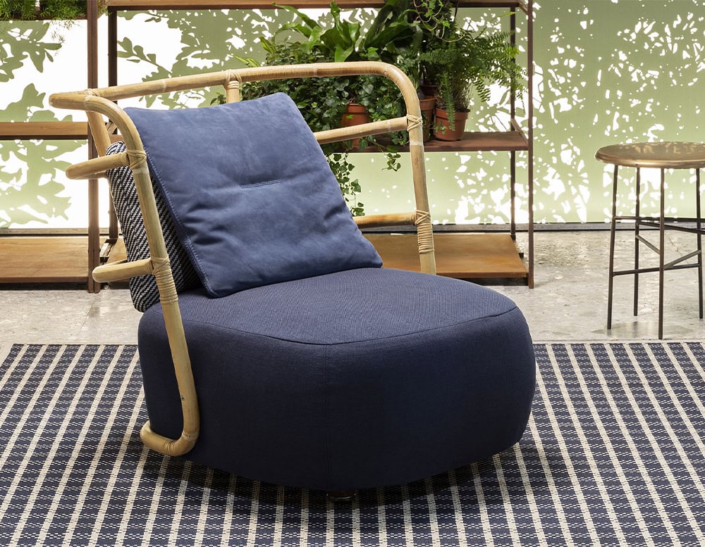 Jungle Armchair Slim upholstered in gray fabric and brown wooden structure in a living room.