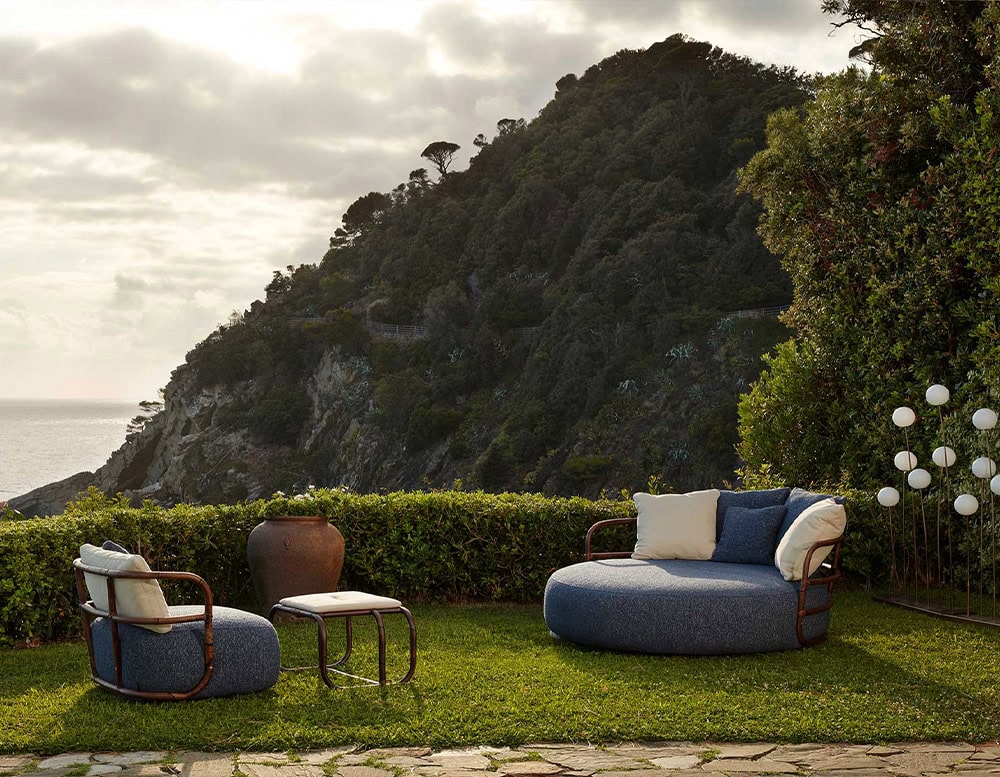 Jungle Daybed upholstered in gray fabric and brown wooden structure on a garden.