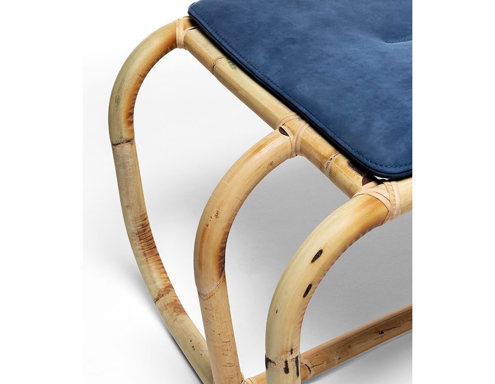 Closeup of Jungle Pouf upholstered in blue fabric and brown wooden structure on a white background.