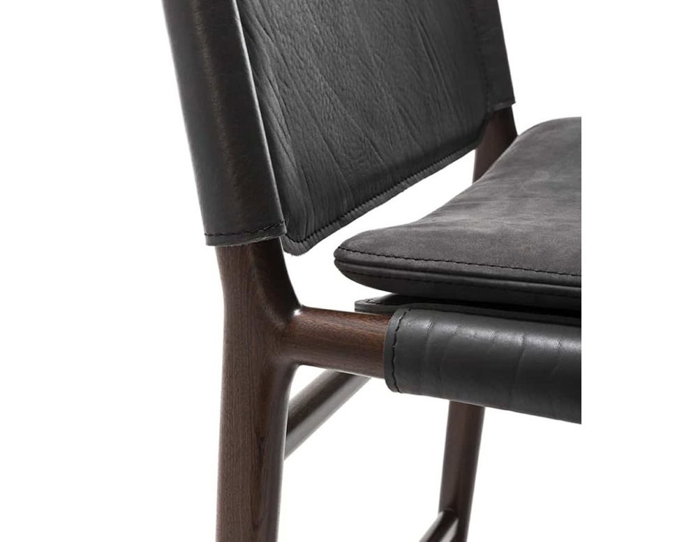 Closeup of Levante Stool. Structure in brown wood, seat and backrest in gray leather and gray cushion on a white background.