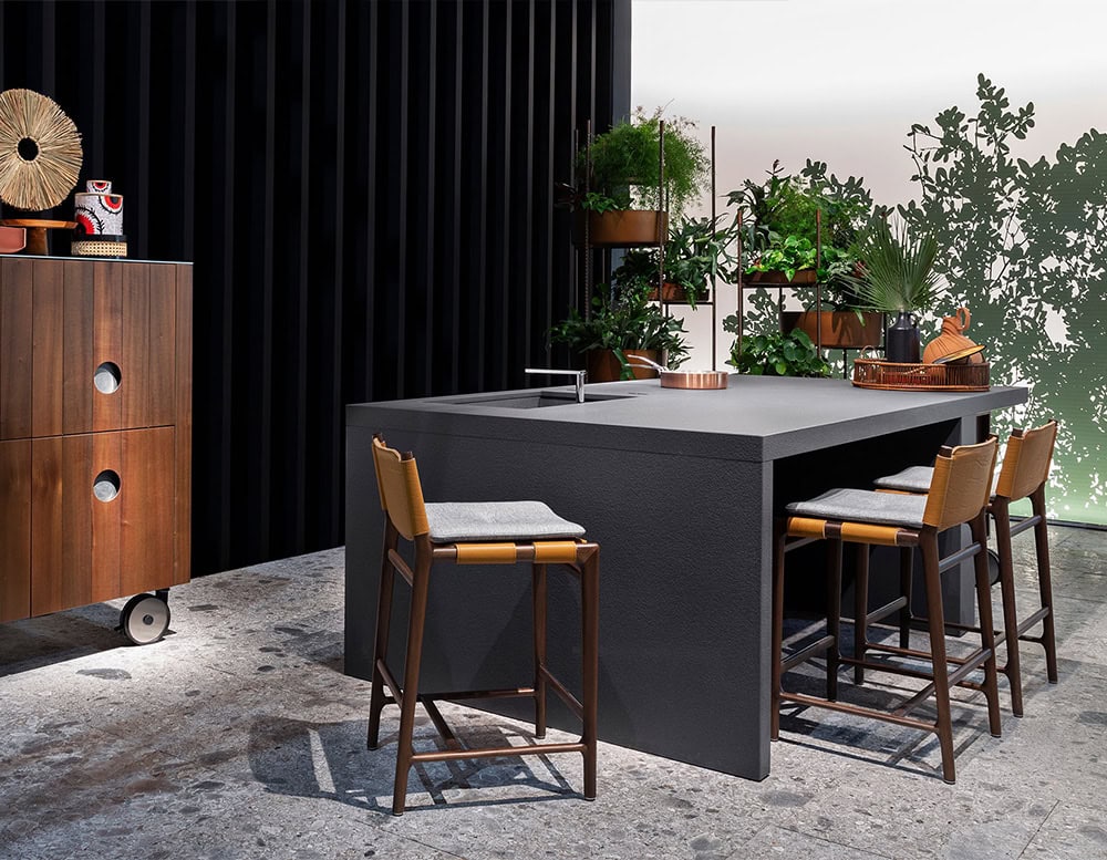 Three Levante Stools. Structure in brown wood, seat and backrest in orange leather ans gray cushion in a kitchen.