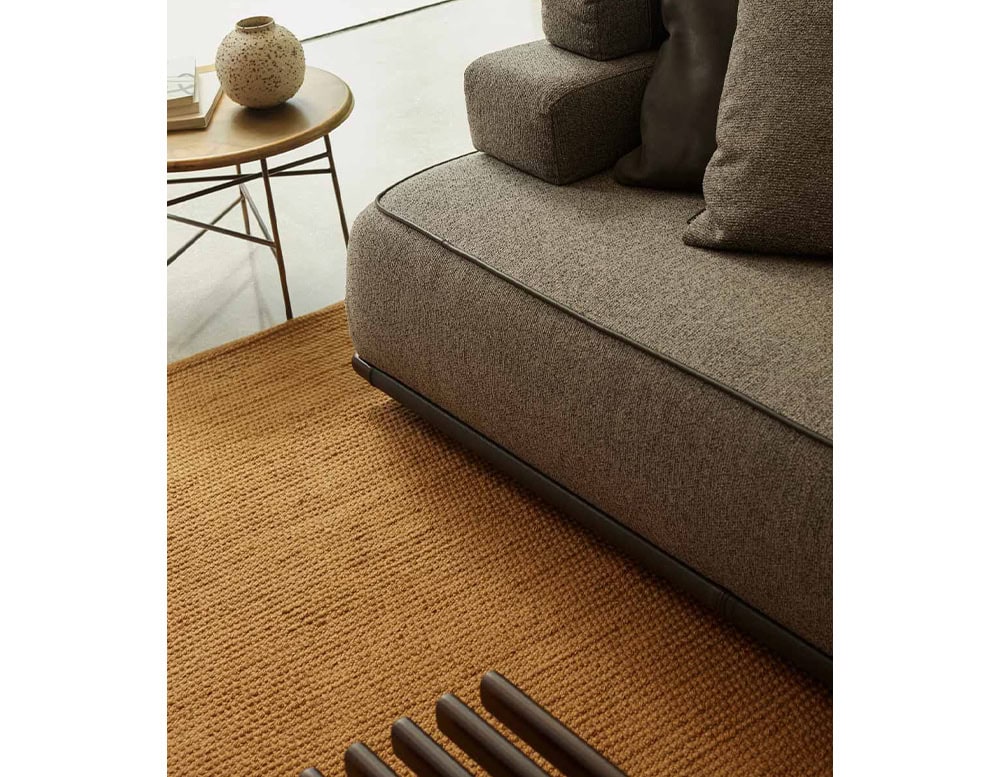 Closeup of Panarea Sofa in gray fabric with backrest and cushions in a living room.
