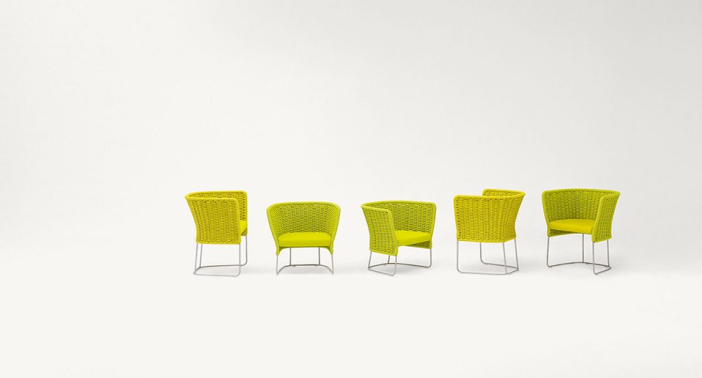 Ami Outdoor Chair: Four woven chairs with a curved backrest, two in yellow and two in green on a white background.