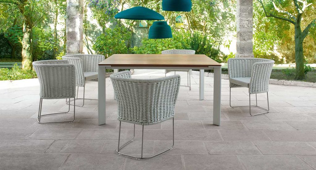 Ami Outdoor Chair: Five white woven chairs with a curved backrest on a terrace.