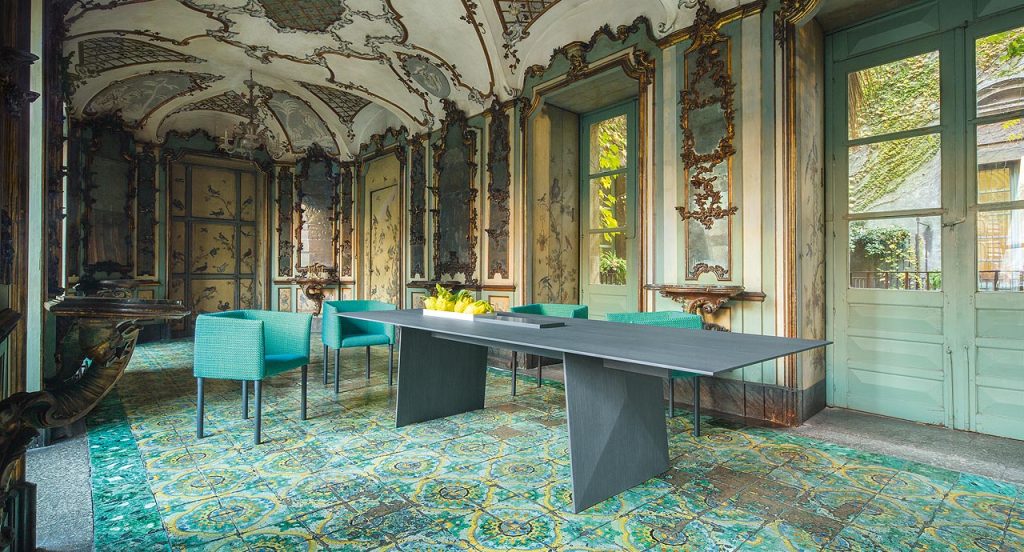 Four Elsie Chairs with armrest, upholstery in blue fabrics, legs in natural heartwood in a dining room.