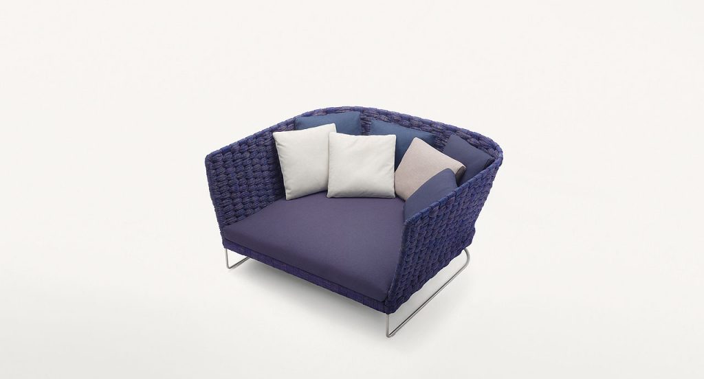 Ami Indoor Sofa: Purple upholstered sofa with woven sides and curved backrest with two silver legs on a white background.