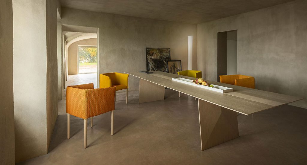 Kanji Dining Table, top in natural fibreboard and two legs in wood and threewhite metal trays in a living room.