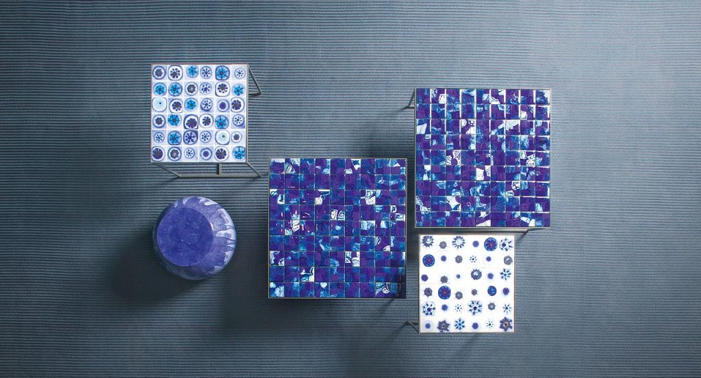 Two Bloom side tables, gray steel structure and legs, top decoration in blue and white glass with irregular patterns in a living room.