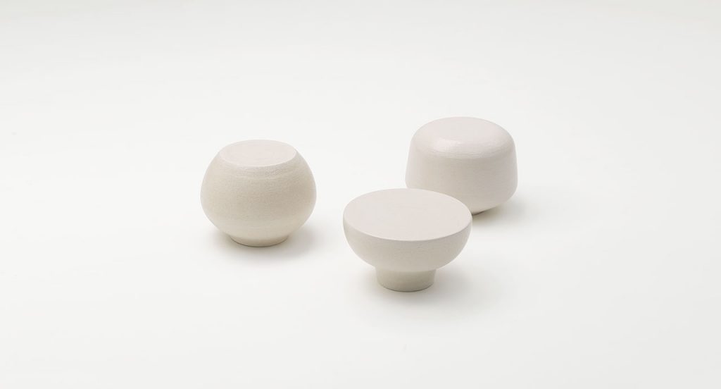 Three white Calatini side tables with abstract shape on a white background.