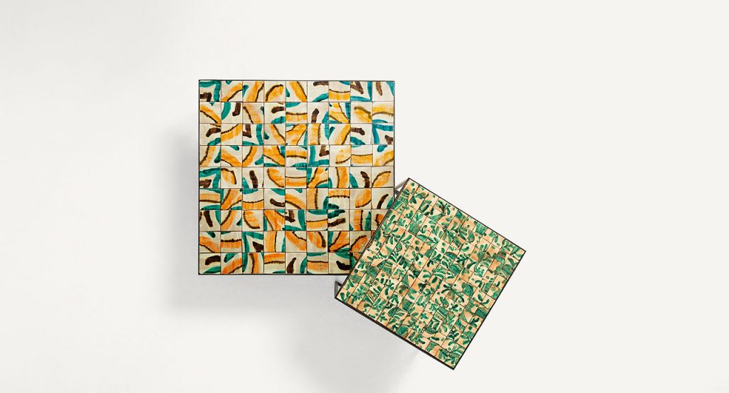 Two Cocci side tables, black steel frame, square ceramic top, one in yellow, blue, white and brown and one in green and yellow on a white background.