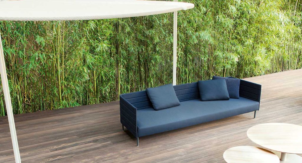 Frame on sofa, legs in black steel, upholstery in blue rope braids, blue seat cushion in a living room.