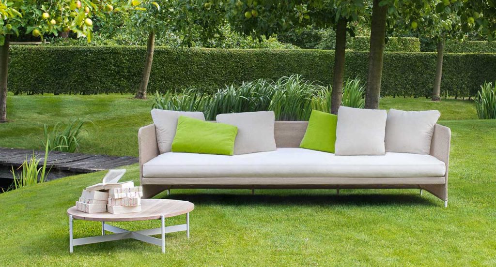 Heron Cofee Table, structure and four legs in white steel, round top in brown in a garden.