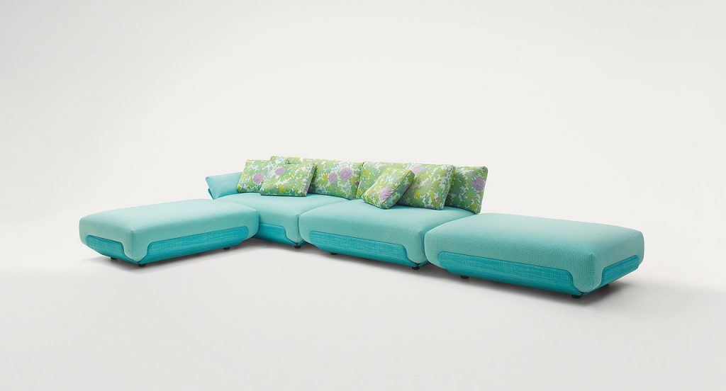 Four blue Oasi, Series of single seatings, two with backrest and one of them with armrest in green and pink garden like patttern on a white background.