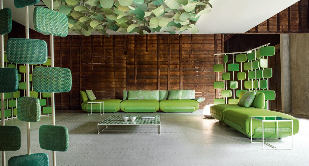 Five blue Oasi, Series of single seatings, three with backrest and one with armrest in green and pink garden like patttern in a living room.