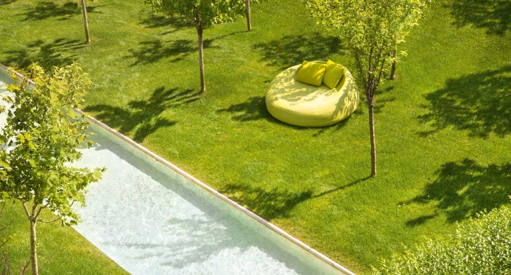 Three Otto Armchairs, upholstery in green rope cord next to a pool.